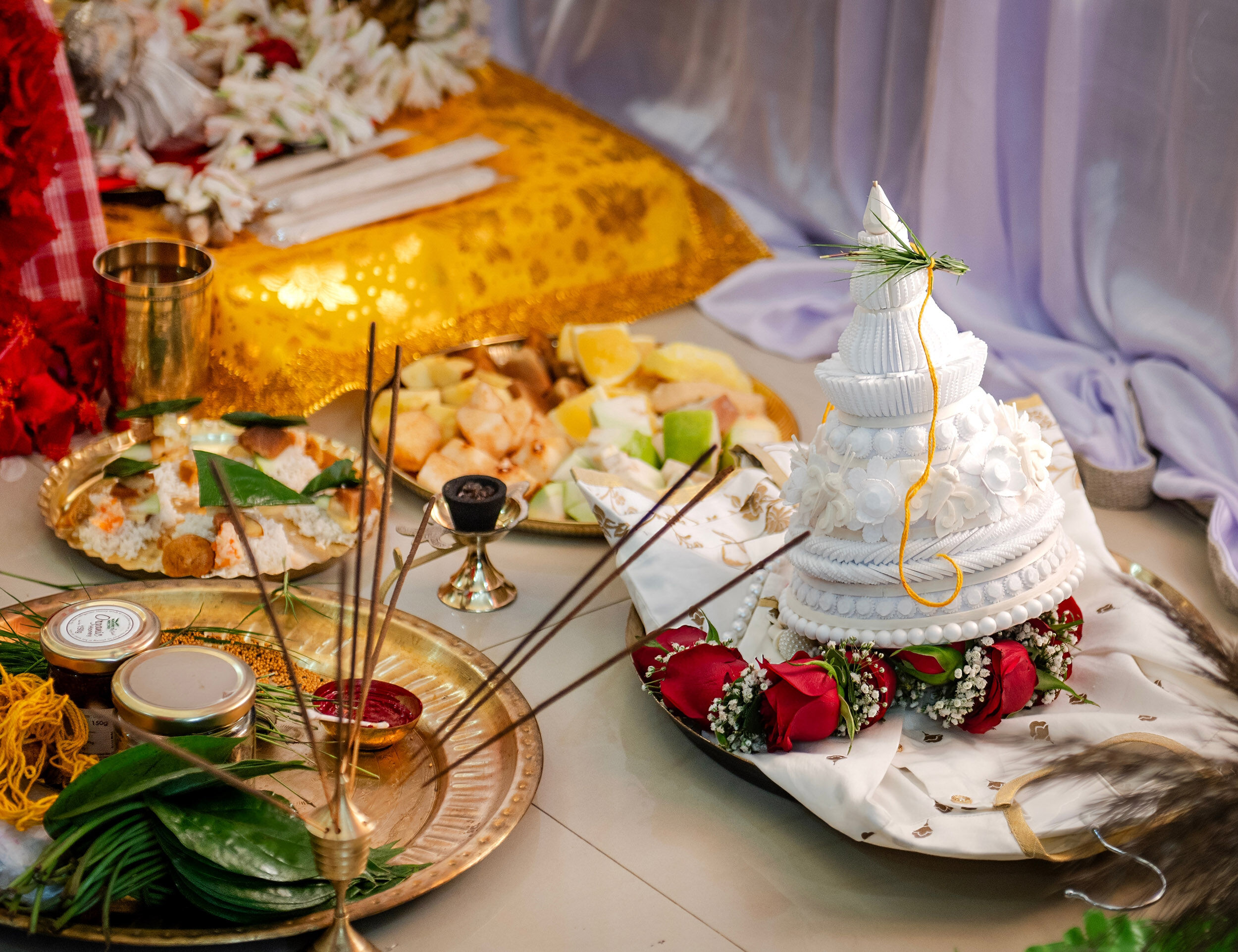 Traditional Bengali wedding items including sindoor, betel leaves, sweets, fruits, and a decorative topor arranged for wedding rituals.